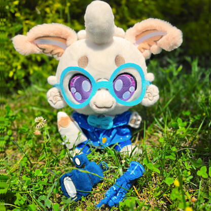 Laisy Luna Moth Plushpanion: A white mothy plush sits on a black mat. The white fluffy moth is wearing light blue glasses, a star (white dot) cobalt blue blazer, with matching navy blue trousers. They're holding a white pencil and dark blue telescope prop.